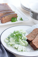 Snack plate with fresh salad from cucumbers and greens, pate from liver, selective focus