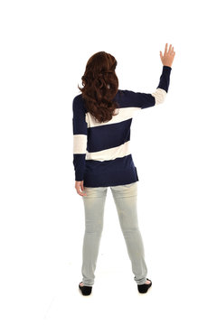 full length portrait of girl wearing striped blue and white jumper and jeans. standing pose  facing away from the camera, on white studio background