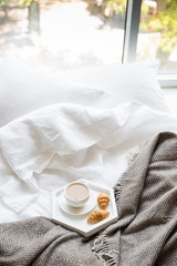 Cozy breakfast in bed, cup of coffee and croissants on white and