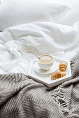 Cozy breakfast in bed, cup of coffee and croissants on white and