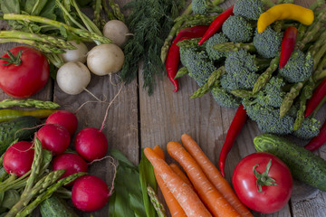 on a wooden table vegetables asparagus, broccoli, chili pepper, radish, carrots, tomato - background of vegetables