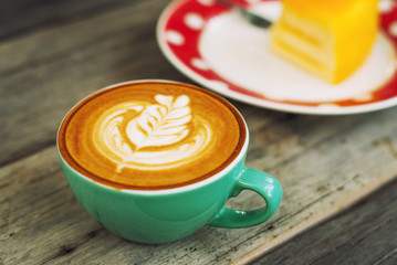 Cappuccino coffee in a green cup on wooden