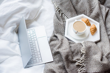 Cozy weekend at home, laptop and coffee in bed