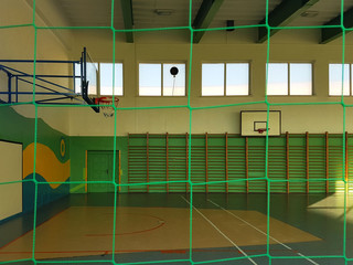 Krosno, Poland - may 27, 2018: Gymnastic multifunctional hall in green colors with a basketball field and a grid on the windows for security. - obrazy, fototapety, plakaty
