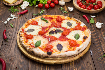 rustic italian pizza Margarita with mozzarella, cherry tomatoes and basil leaves on wooden...