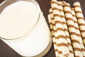 a glass of yogurt with a waffle straw on a black background and a brick wall