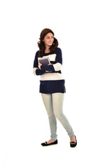 full length portrait of girl wearing striped blue and white jumper and jeans and holding a book. standing pose on white studio background