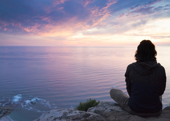 A young woman watching a beautiful sunset over the ocean