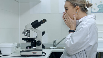 Surprised woman working with a microscope in laboratory