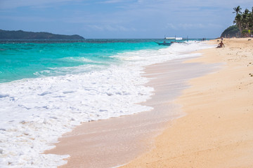 tourists and boats at white Puka beach of Boracay island Philippines