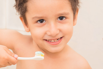 brown-eyed boy brushing his teeth in the bathroom