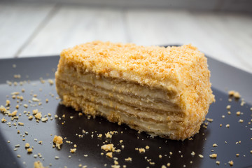 Piece of cake Napoleon on black plate . Dessert concept