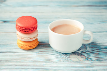 Cup of coffee with macarons on a blue wooden background. Selective focus.