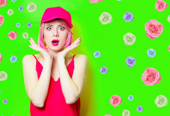 portrait of beautiful surprised young woman in cap with roses on the wonderful green studio background
