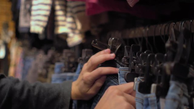 Female hands choosing chinos in the clothing store Close-up with changing focus