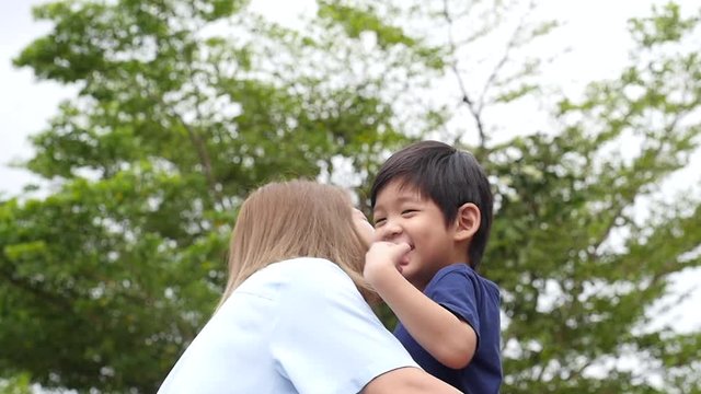 Asian mother carry herson in the park on summer day slow motion 