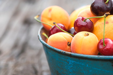 Summer berries and fruits. Apricots and cherries in a blue bowl. Close-up