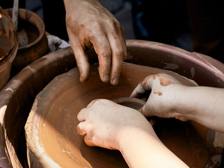 Pottery training. The hands of the pupil and master over the potter.