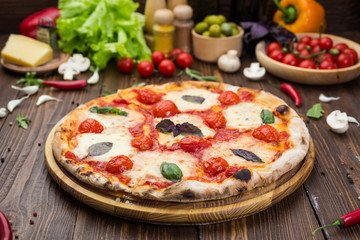 rustic italian pizza Margarita with mozzarella, cherry tomatoes and basil leaves on wooden background