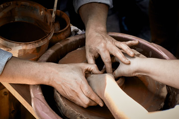 Pottery training. The hands of the pupil and master over the potter.