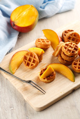 circle mini waffles with mango on wooden cutting board. Top view