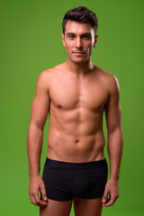 Fototapeta premium Young handsome Hispanic man shirtless against green background