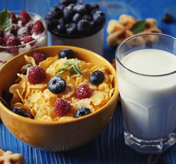 Healthy breakfast. Corn flakes with raspberries and blueberries, granola with yogurt and berries, wafers and milk. A great start to the day. Top view.
