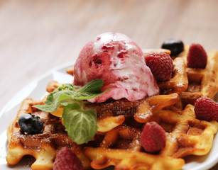 Plate of belgian waffles with ice cream and fresh berries - raspberries and blueberries