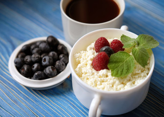 Russian cottage cheese with berry and mint, blueberries and coffee on wooden table.