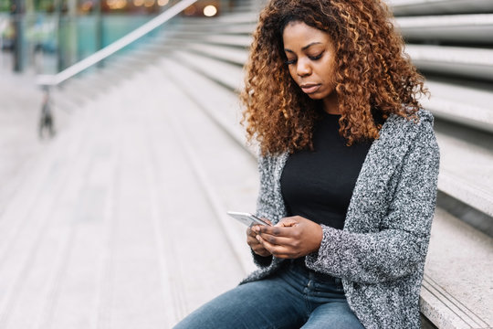 Portrait of young black woman using mobile phone