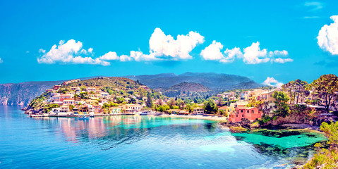 Beautiful landscape with bay and colorful buildings on the background of picturesque clouds in the town of Asos, Greece, Kefalonia. Wonderful exciting places. Panorama. - obrazy, fototapety, plakaty