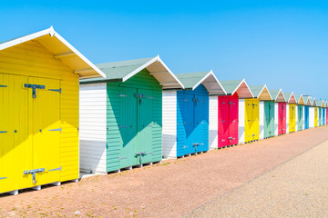 Fototapeta na wymiar A row of colorful wooden beach huts on the beach in Eastbourne, East Sussex, UK
