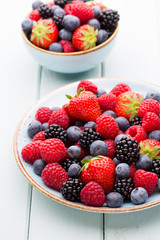 Fresh berry salad on blue dishes. Vintage wooden background.