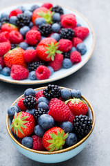 Fresh berry salad on blue dishes. Vintage wooden background.