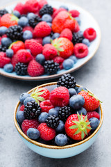 Fresh berry salad on blue dishes. Vintage wooden background.