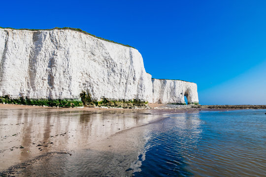 View of white chalk stacks and cliffs, sea at low tide and beach in Kingsgate Bay, Margate, East Kent, UK