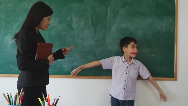 Young asian student laughing while his teacher punish him in classroom