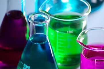 A closeup photo for a group of laboratory glassware containing colored liquids