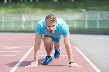 Man runner on start position at stadium. Runner in start pose on running surface. Man run outdoor...