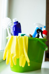 Plastic green bucket with cleaning supplies on window. Equipment for house cleaning