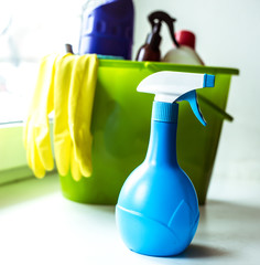 Plastic green bucket with cleaning supplies on window. Equipment for house cleaning