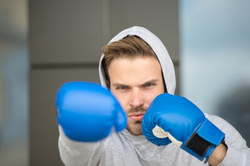 Boxing concept. Man athlete on concentrated face with sport gloves practicing boxing punch, urban...