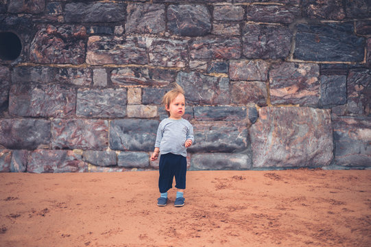 Little boy by big wall on the beach