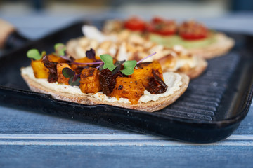 Rustic skillet made open faced sandwiches on a blue table