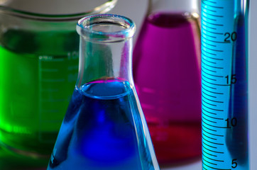 Flasks , beaker , and a measuring cylinder on a white table in chemistry laboratory