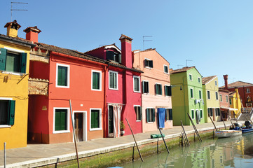 Fototapeta na wymiar Panoramic view of colorful buildings and boats in front of a canal, in a sunny day at Burano, a gracious little town full of canals, near Venice. Located in the Veneto region, northern Italy