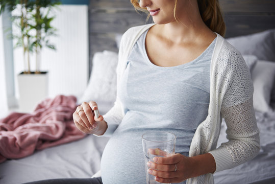 Young pregnant woman taking capsule