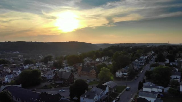A slow forward aerial establishing shot of a residential neighborhood in a small Pennsylvania town at sunset. Pittsburgh suburbs.  	