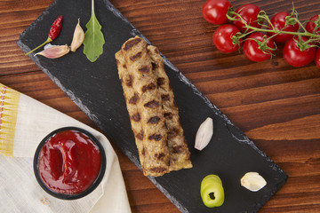 Grilled Veal minced meat with spices on black stone and wooden background 