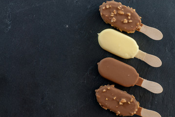 assorted mini ice creams on stick on black with copy space